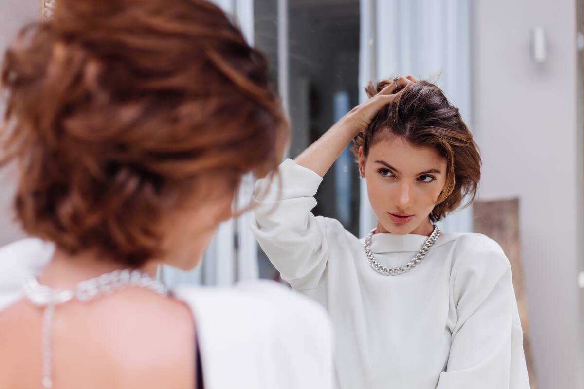 A young woman admiring herself in a mirror.