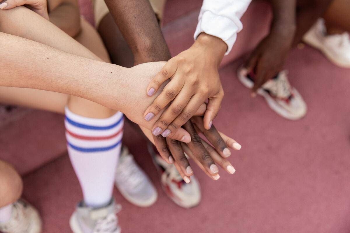 Teammates all stacking their hands together in a cheer.