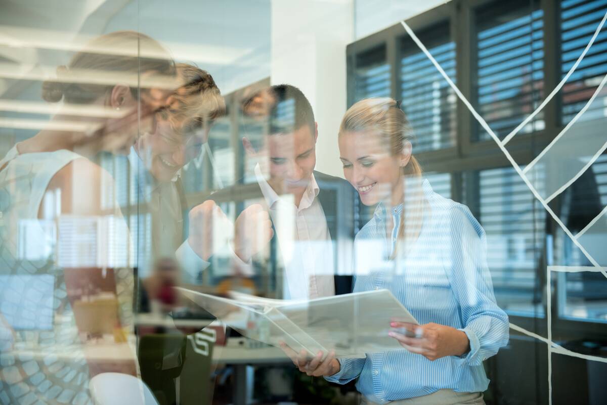 Successful business team behind glass wall in office looking at folder.