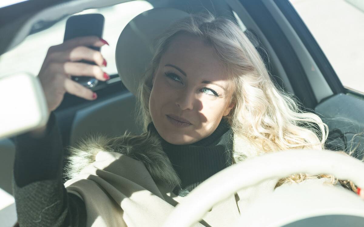 A woman taking a selfie in her car.