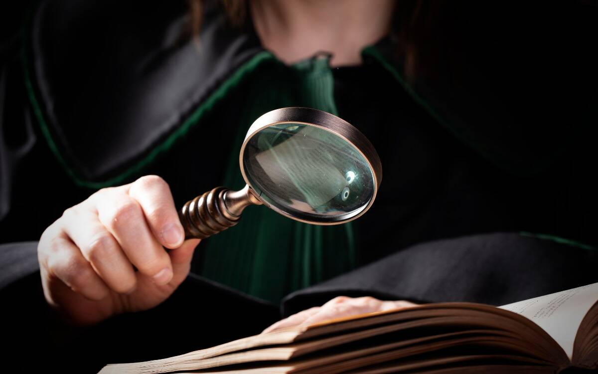 Someone holding up a magnifying glass to read the pages of a book.