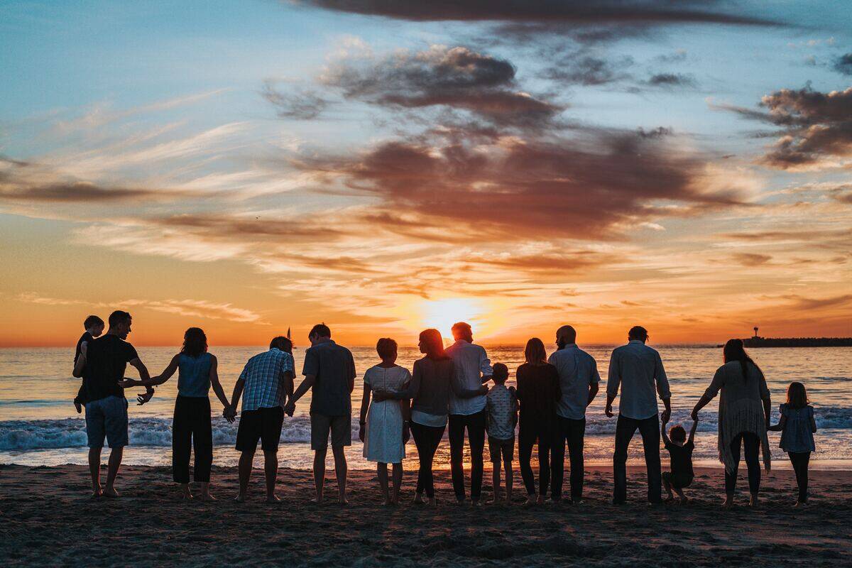 A large family lined up on a beach, silhouetted by the setting sun.