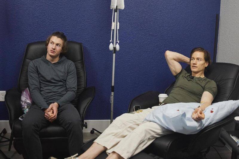 Bryan and Talmage sitting in large black chairs during their blood transfusion process.