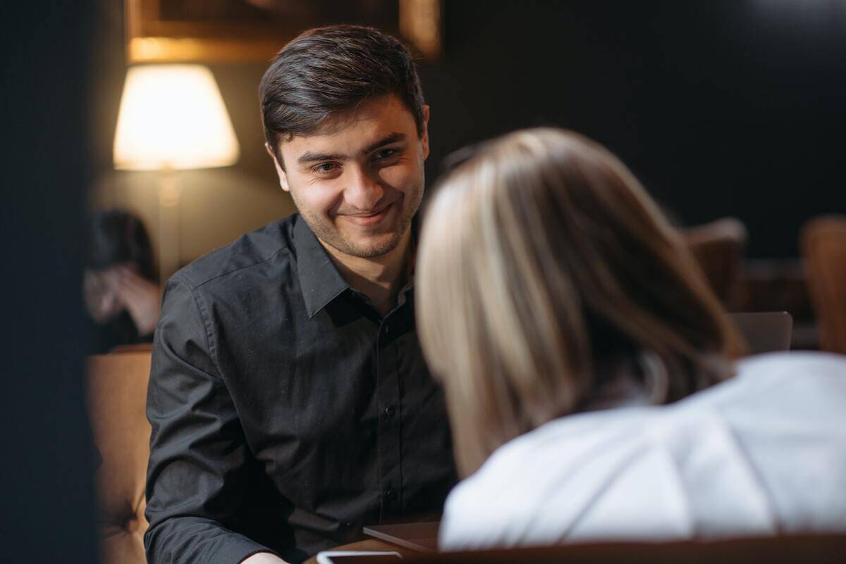 A man and a woman sitting at a table, the man smiling at the woman.