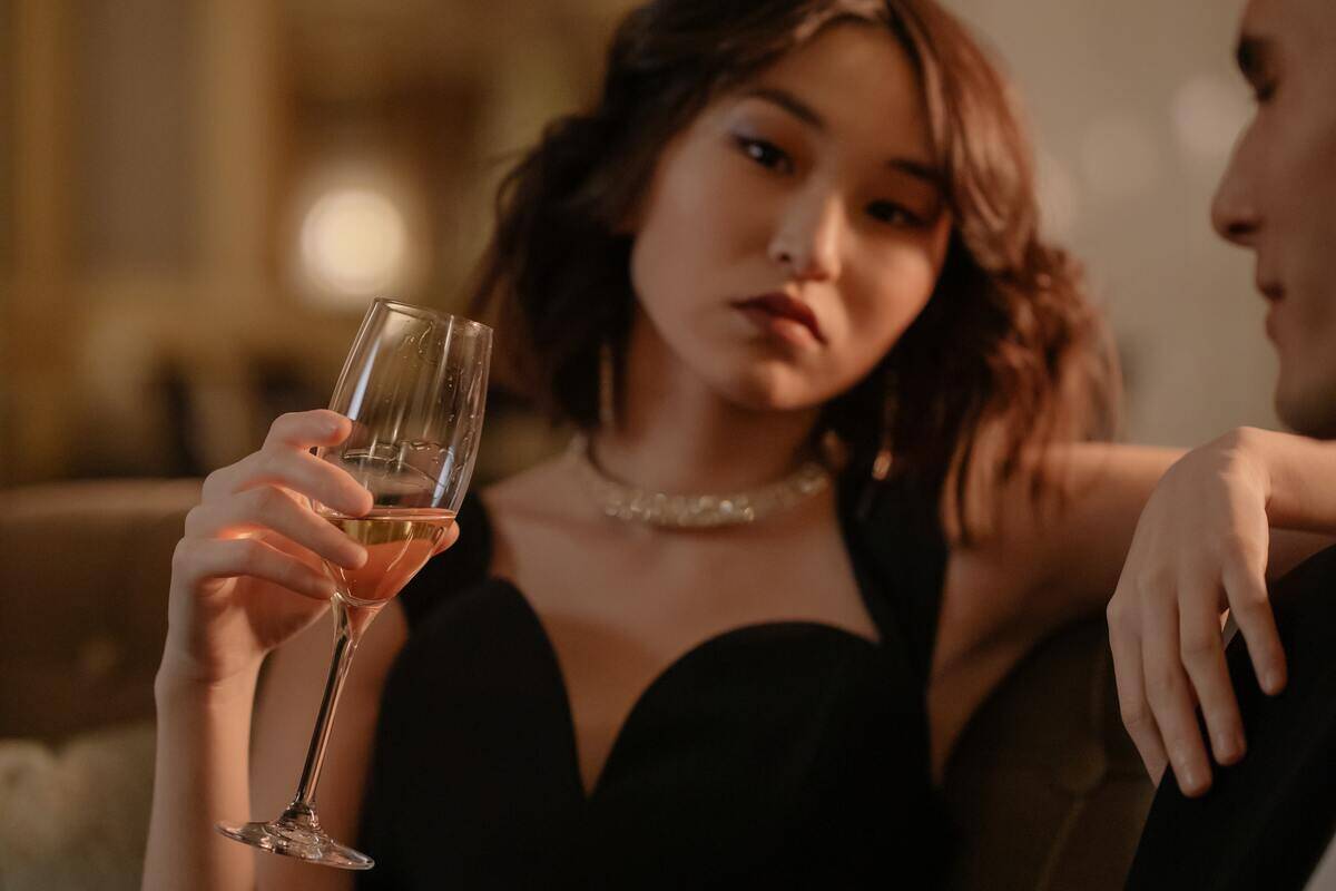 A woman lounging on a couch with a glass of champagne in her hand.