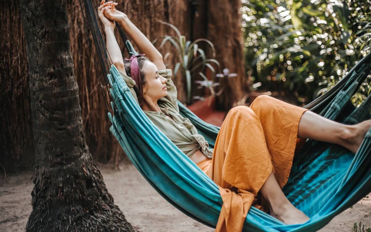 A woman relaxing in a hammock between some trees.