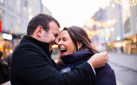 A couple embracing on the street, laughing with one another.