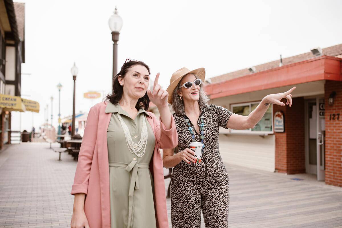 Two women walking along a boardwalk, pointing at attractions ahead of them.