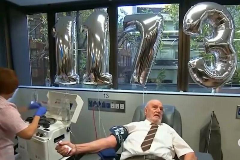 James in the clinic chair, preparing to give blood with balloons that read '1173' behind him.