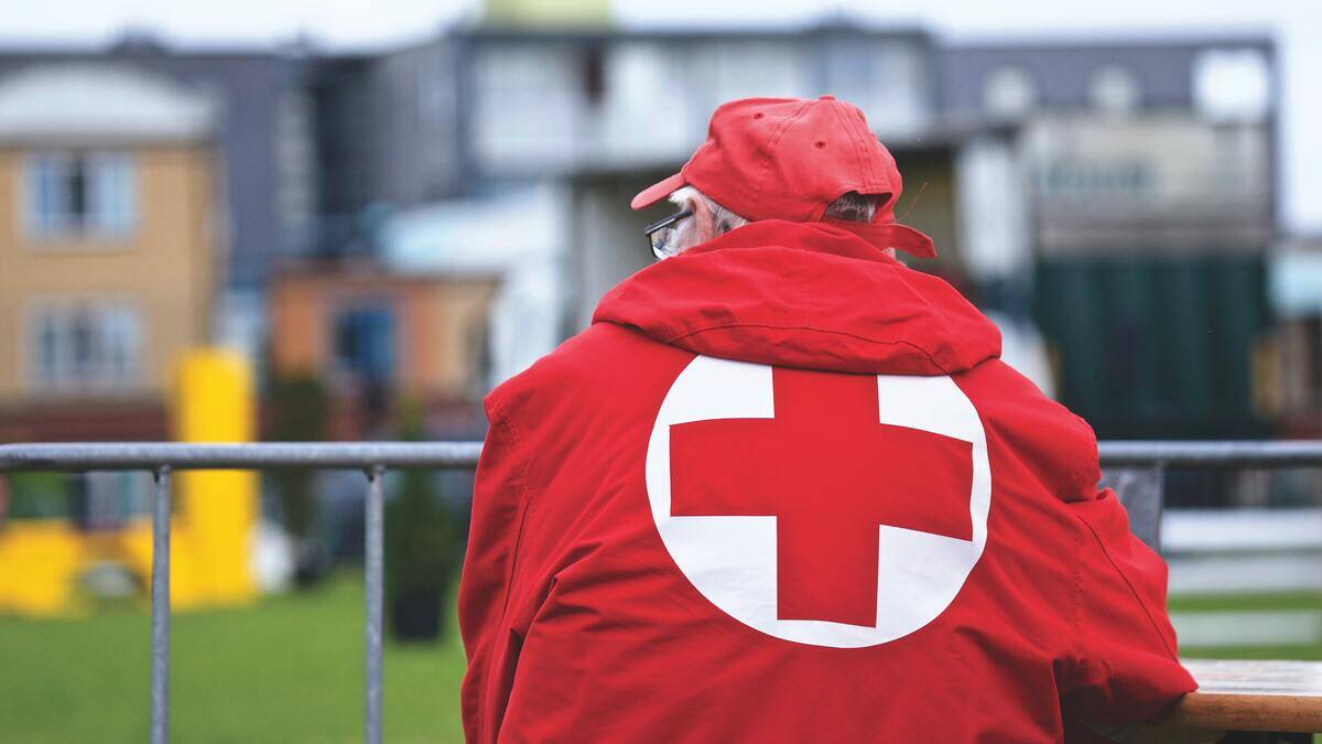 A man in a volunteer paramedic jacket watching over a railing.