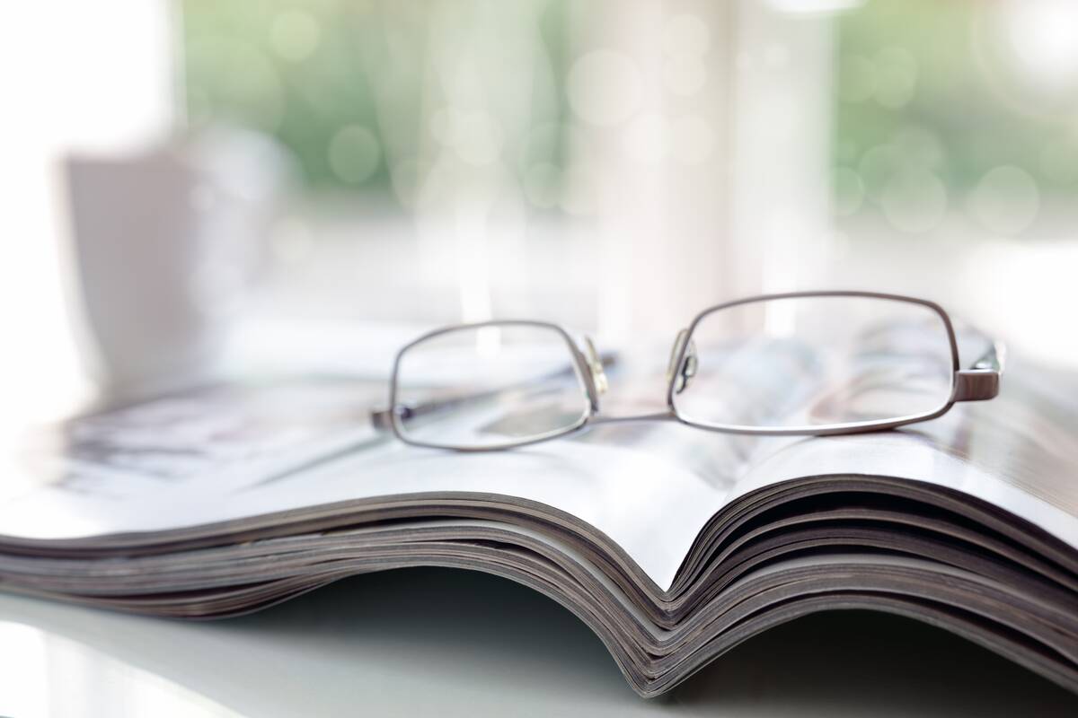 Magazines on a desk with reading glasses