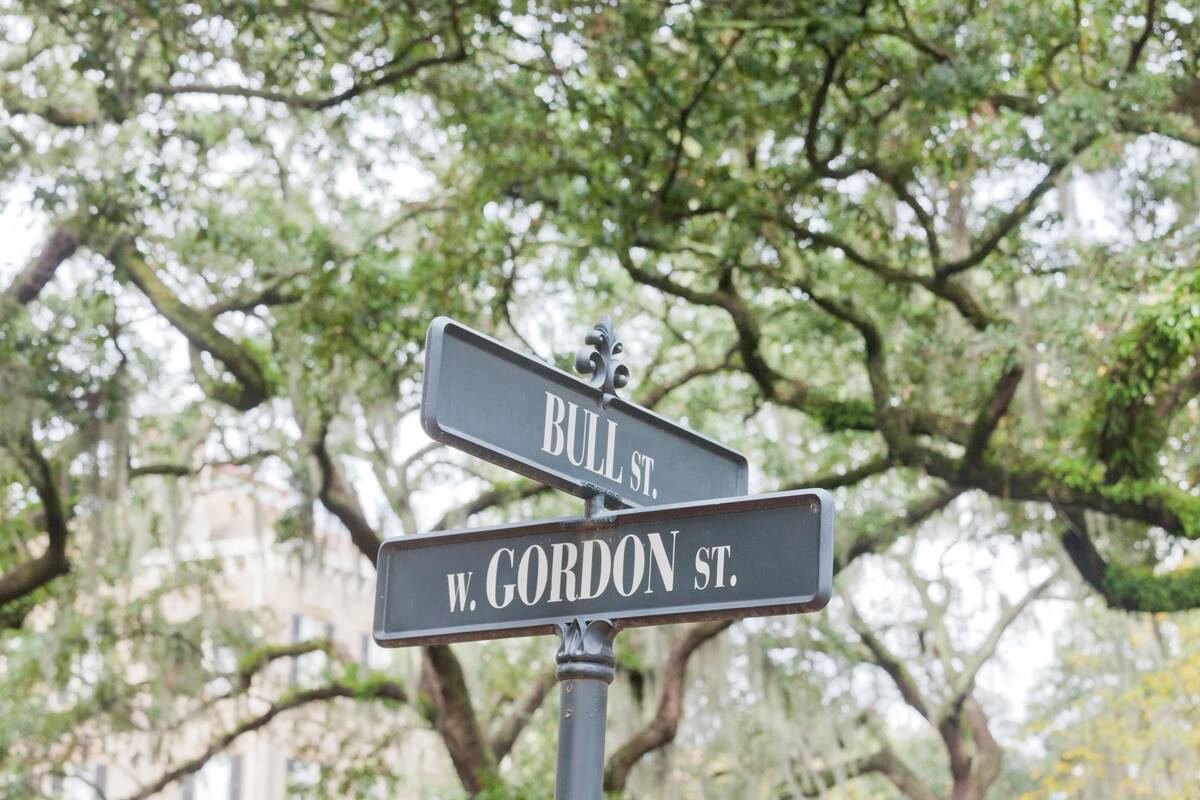 Street name signs of Bull Street corner West Gordon Street under oak trees of Monterey Square in Historic District of downtown city of Savannah, Georgia, GA, USA