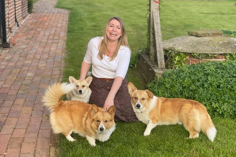 Pettit kneeling on her lawn with her three corgis.
