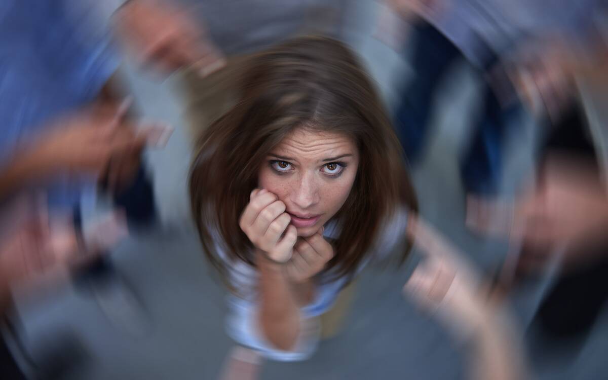 A woman looking anxious, in the middle of a spinning blur, with people pointing fingers all around her.