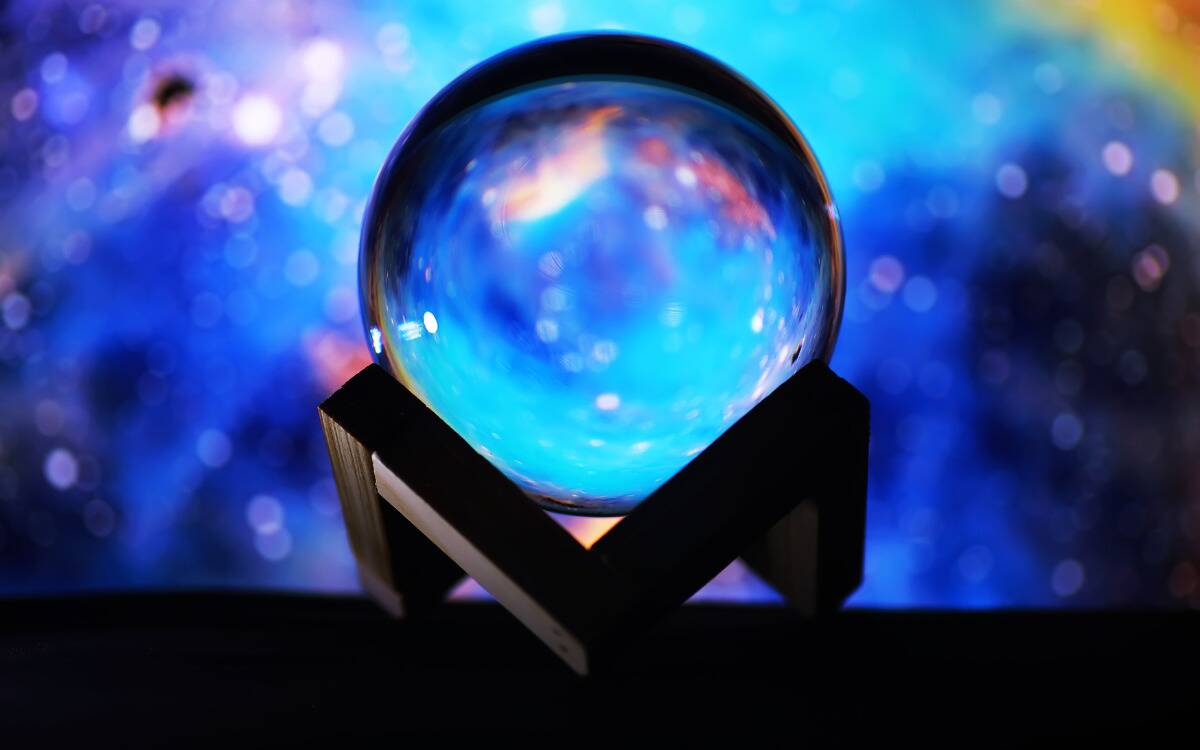 A crystal ball on a stand in front of a colorful space background.