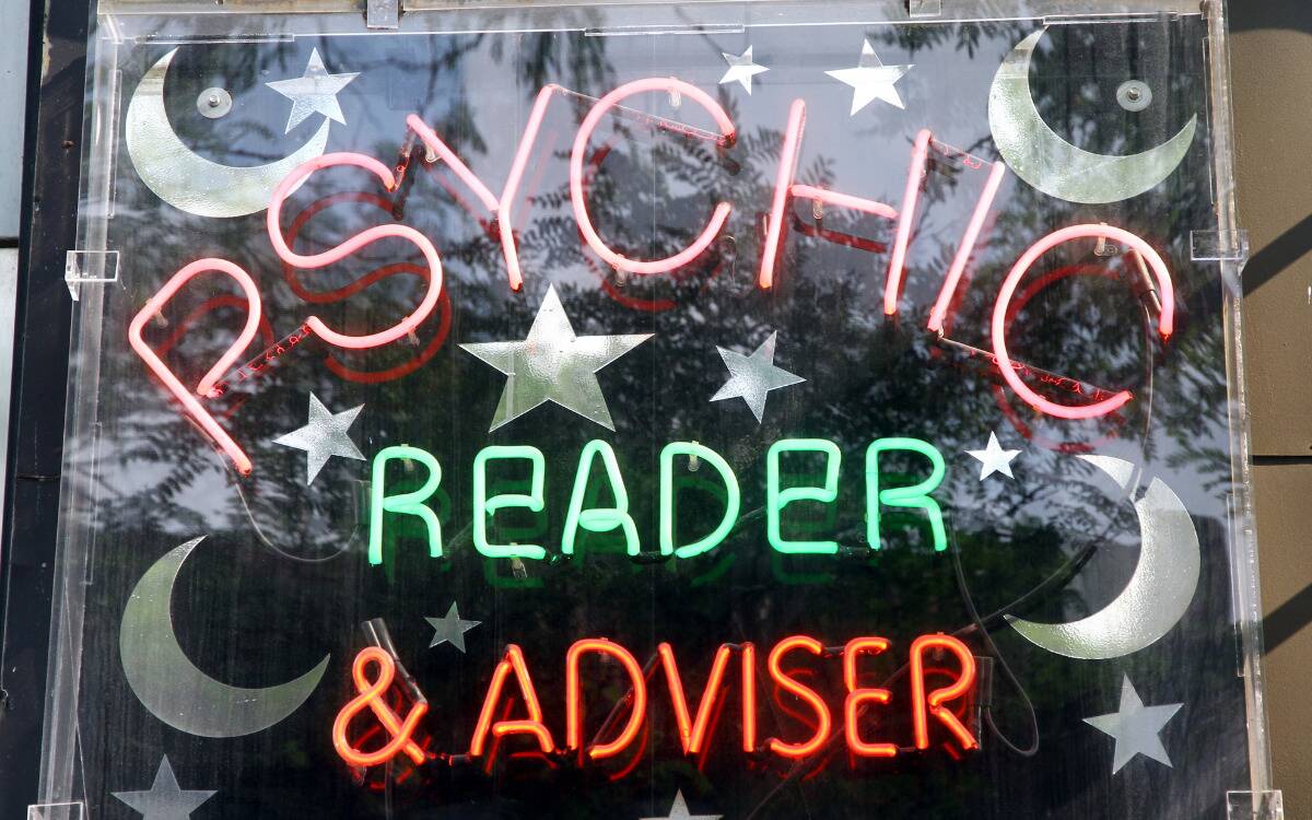 A neon sign in a window advertising a psychic reader.