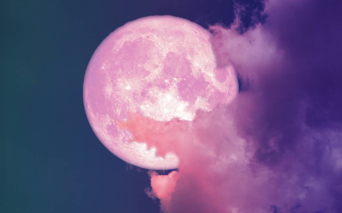 A large pin moon among pink clouds in the sky.