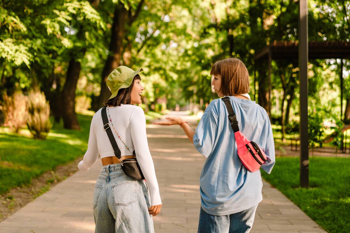 Multiracial two women talking and gesturing while walking together