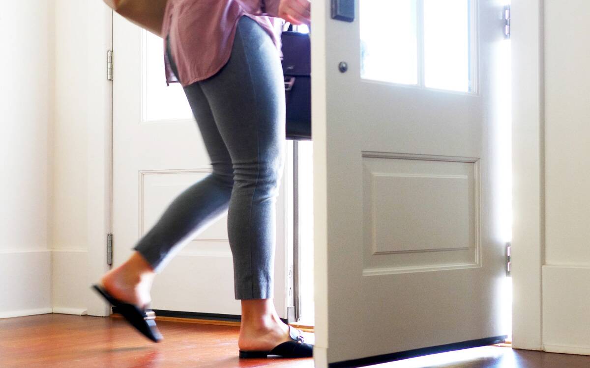 A woman walking out a house front door.