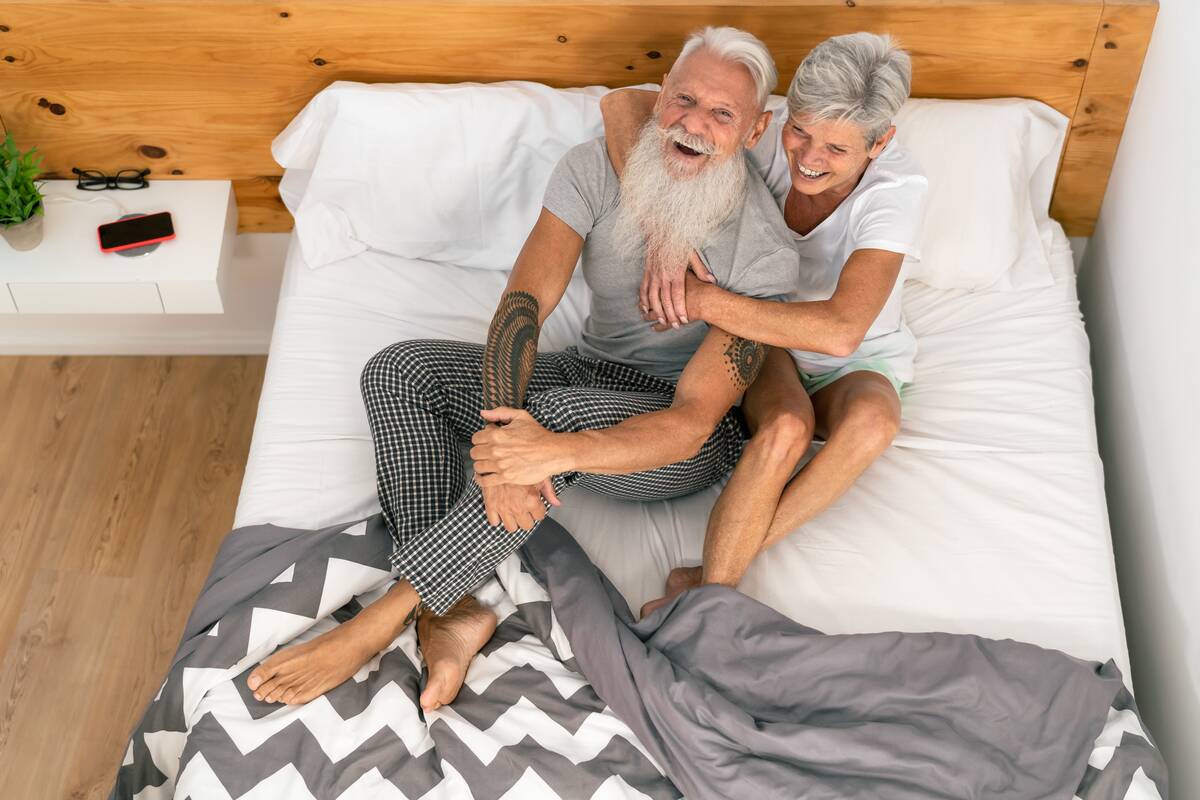 Happy senior couple smiling together in bed, smiling with each other.