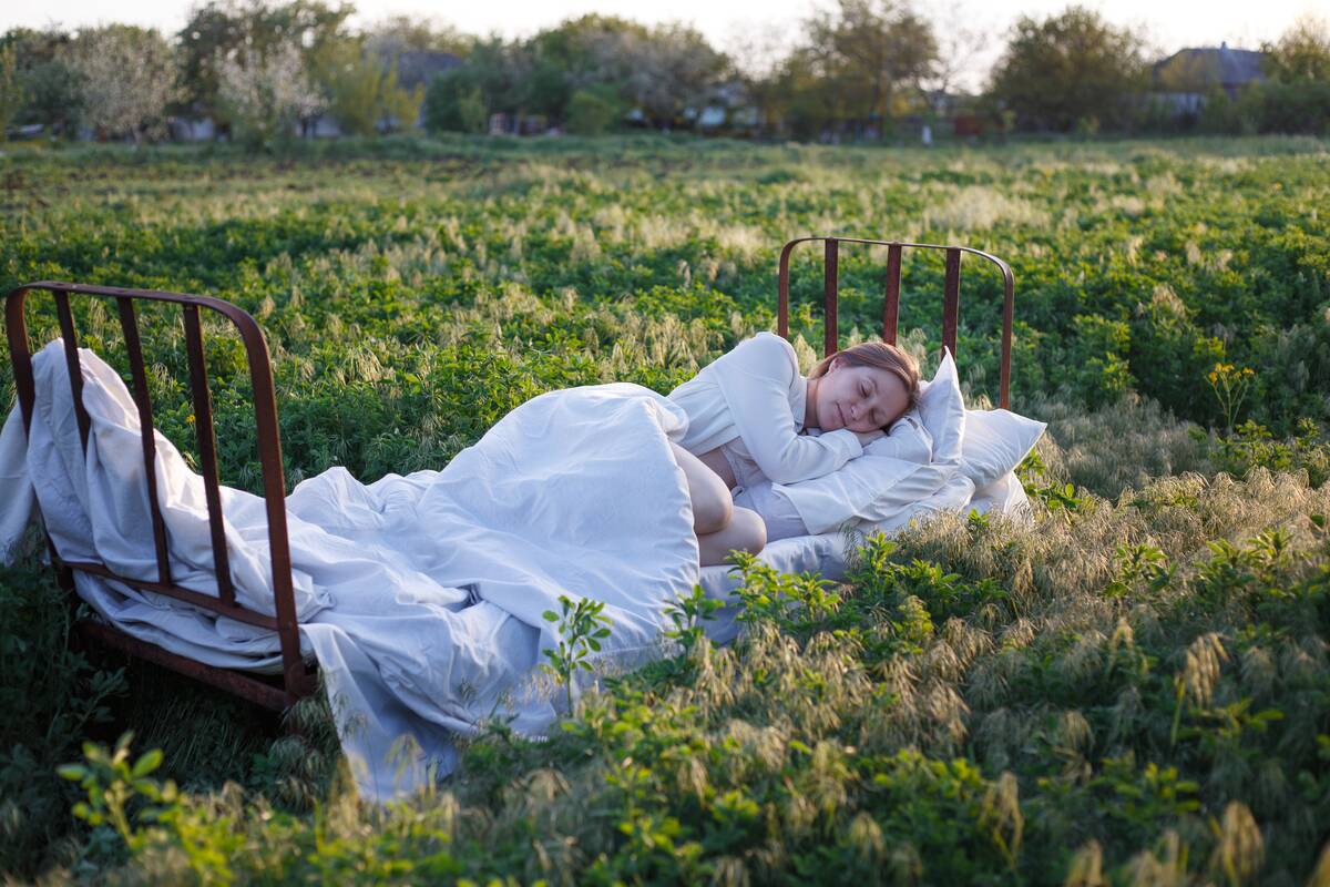 Girl sleeping in the bed in a green field.