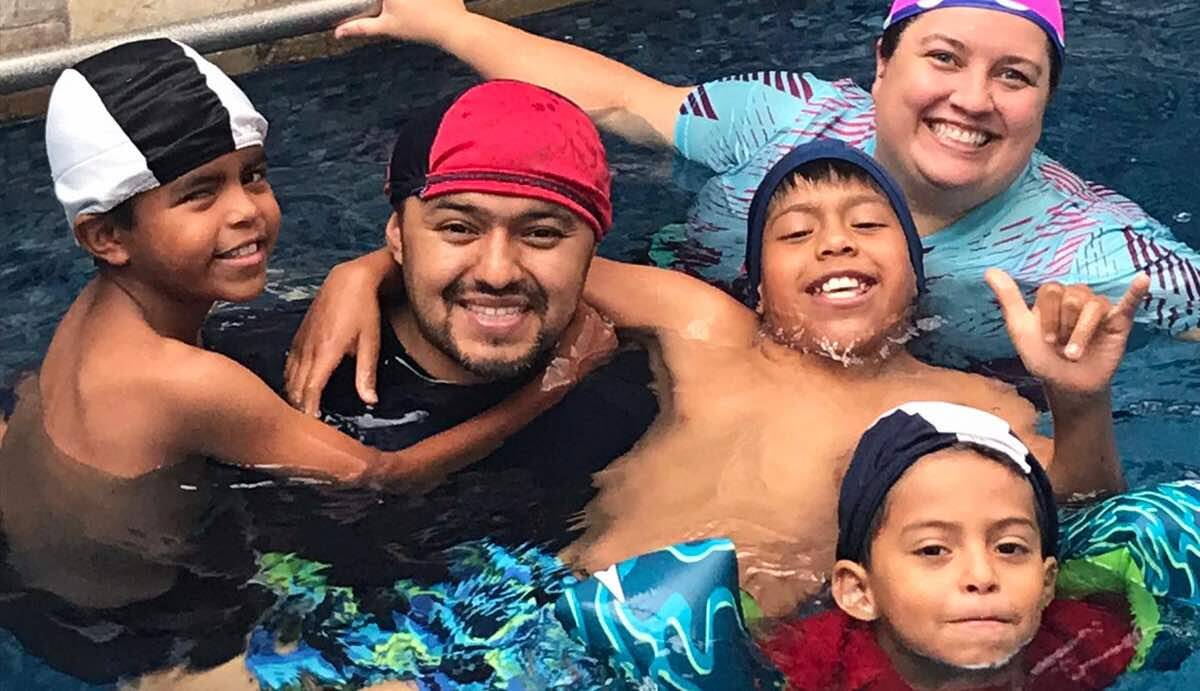 Darwin, Josue, and Abraham swimming with their adopted parents, Nicole and David.
