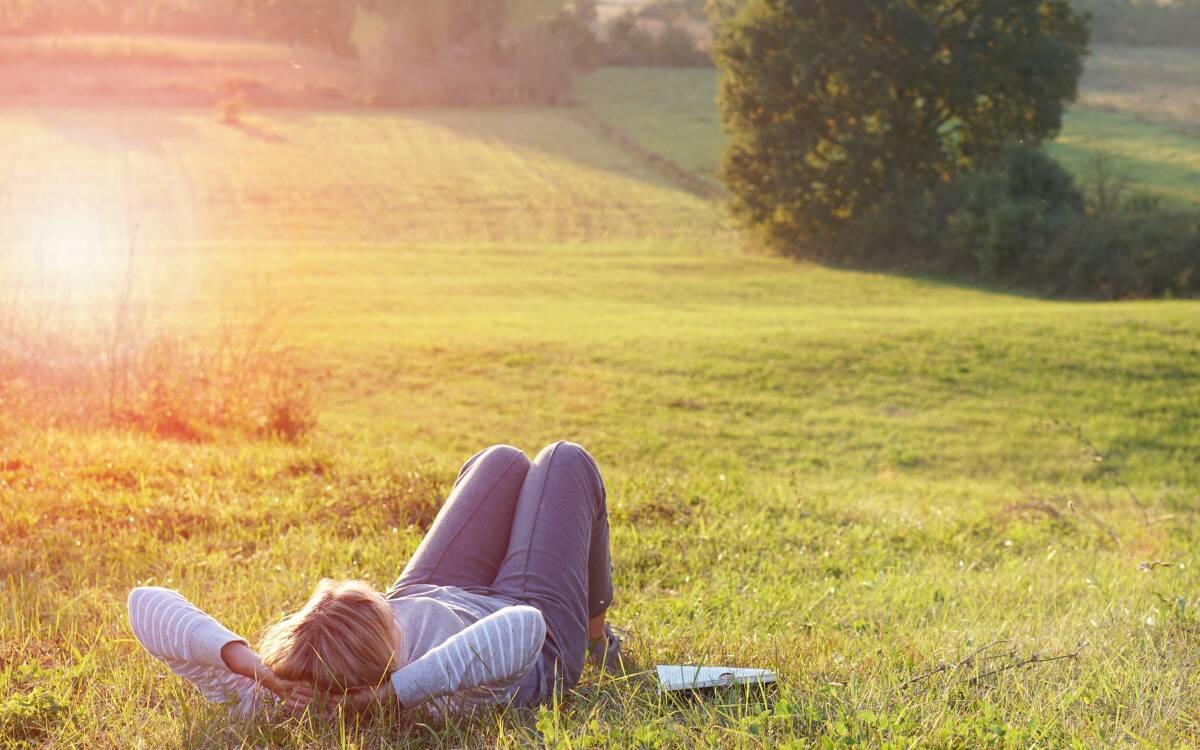 A woman laying in the grass in a field.