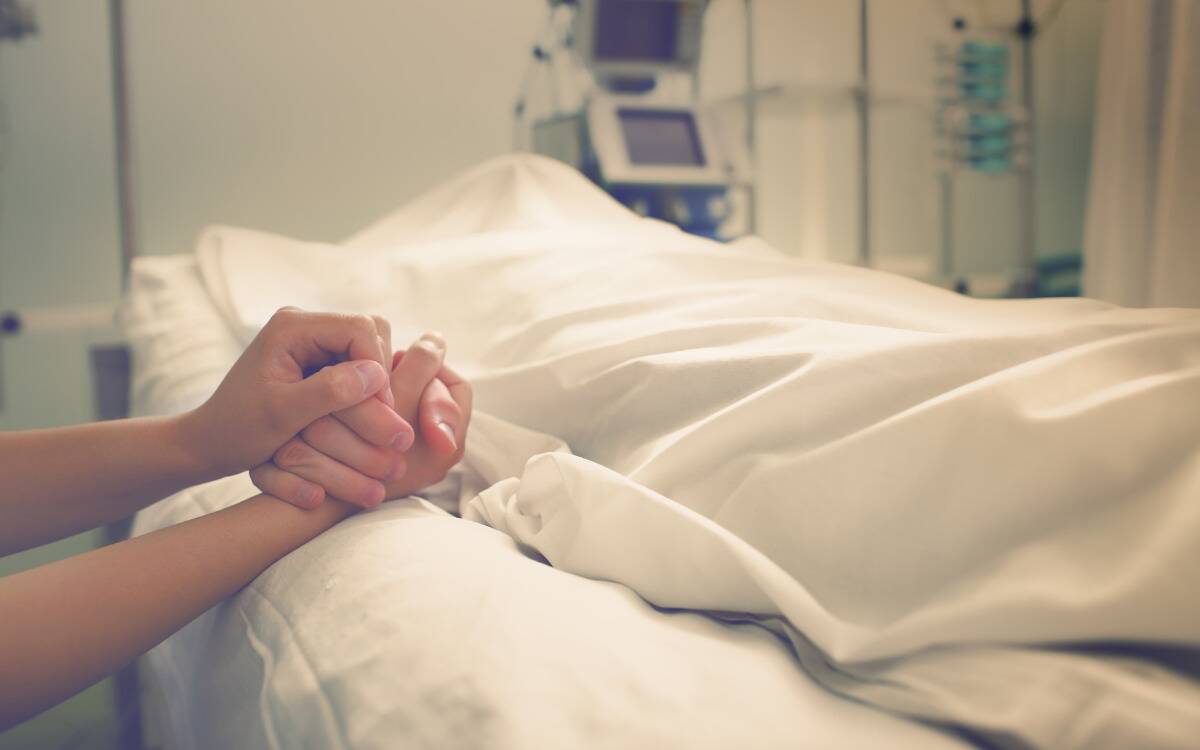 A body covered by a bedsheet on a hospital bed.