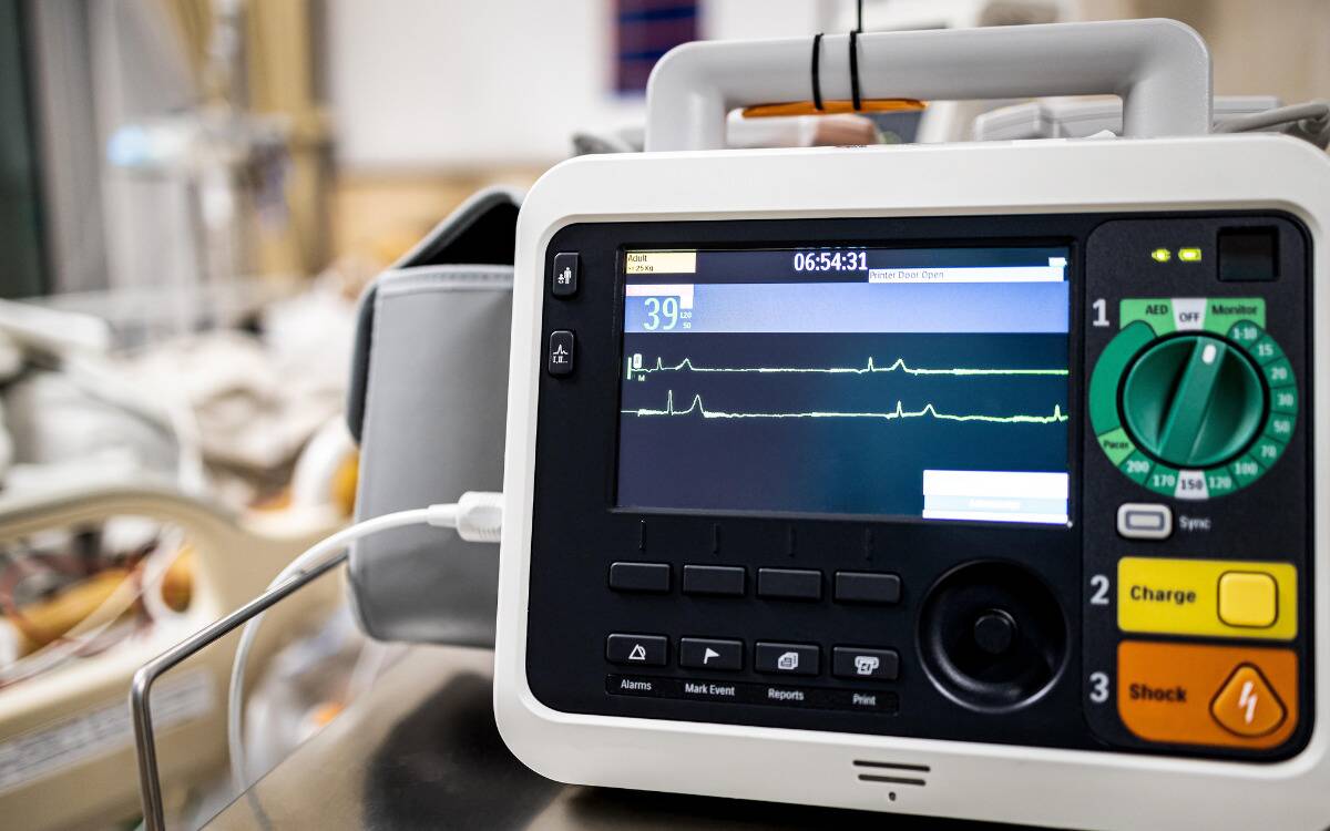 A heart rate monitor next to a hospital bed in the background.