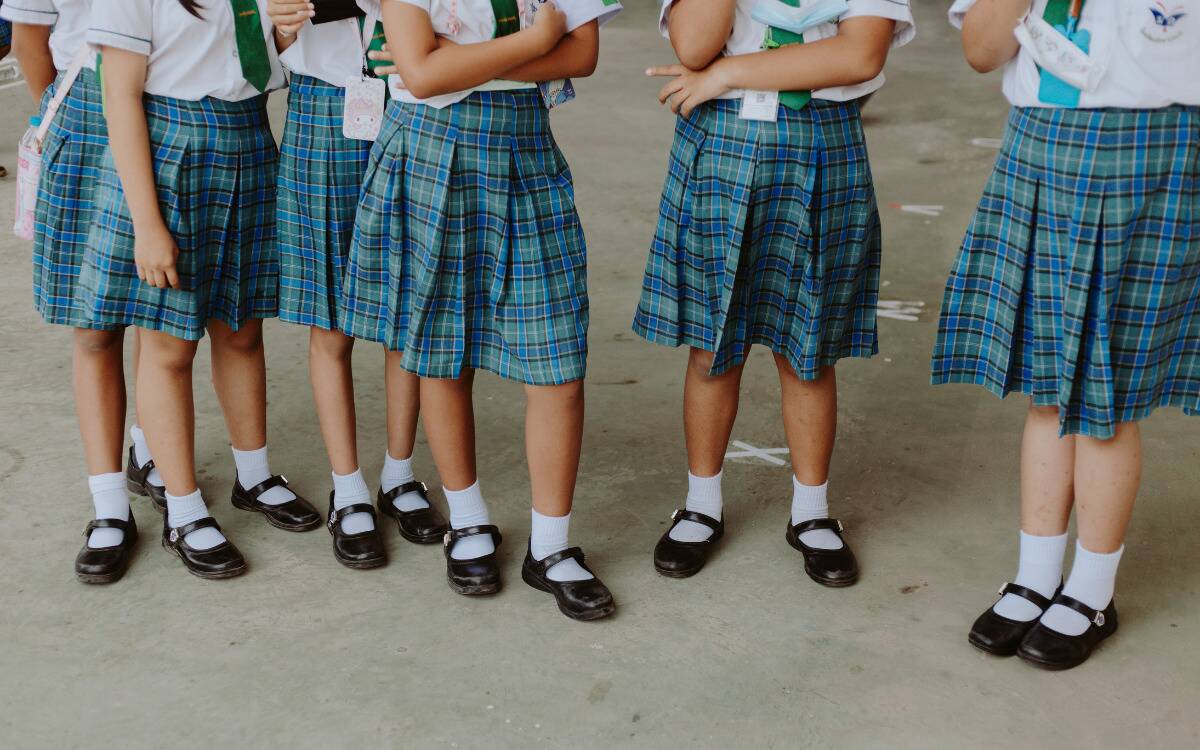 Three girls standing next to each other, all in their school uniforms.