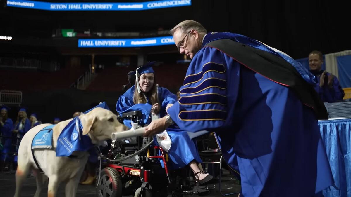 Justin the service dog on stage receiving his diploma.