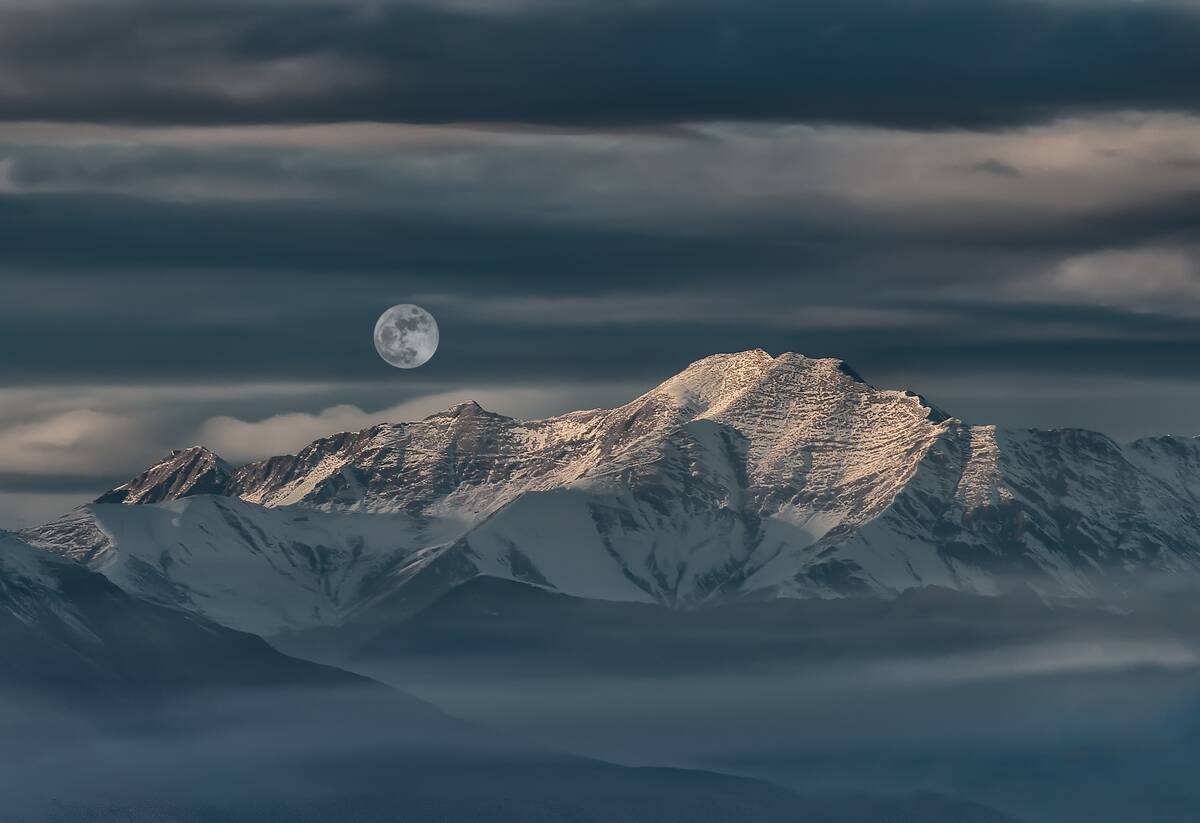 Landscape of mountain and desert with snow with full moon