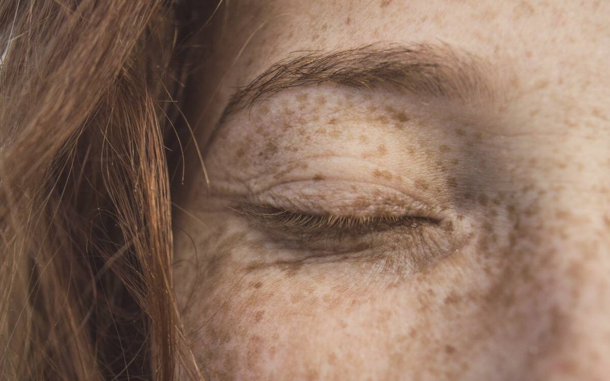 A closeup of a woman's closed eye, showing her eyebrow.
