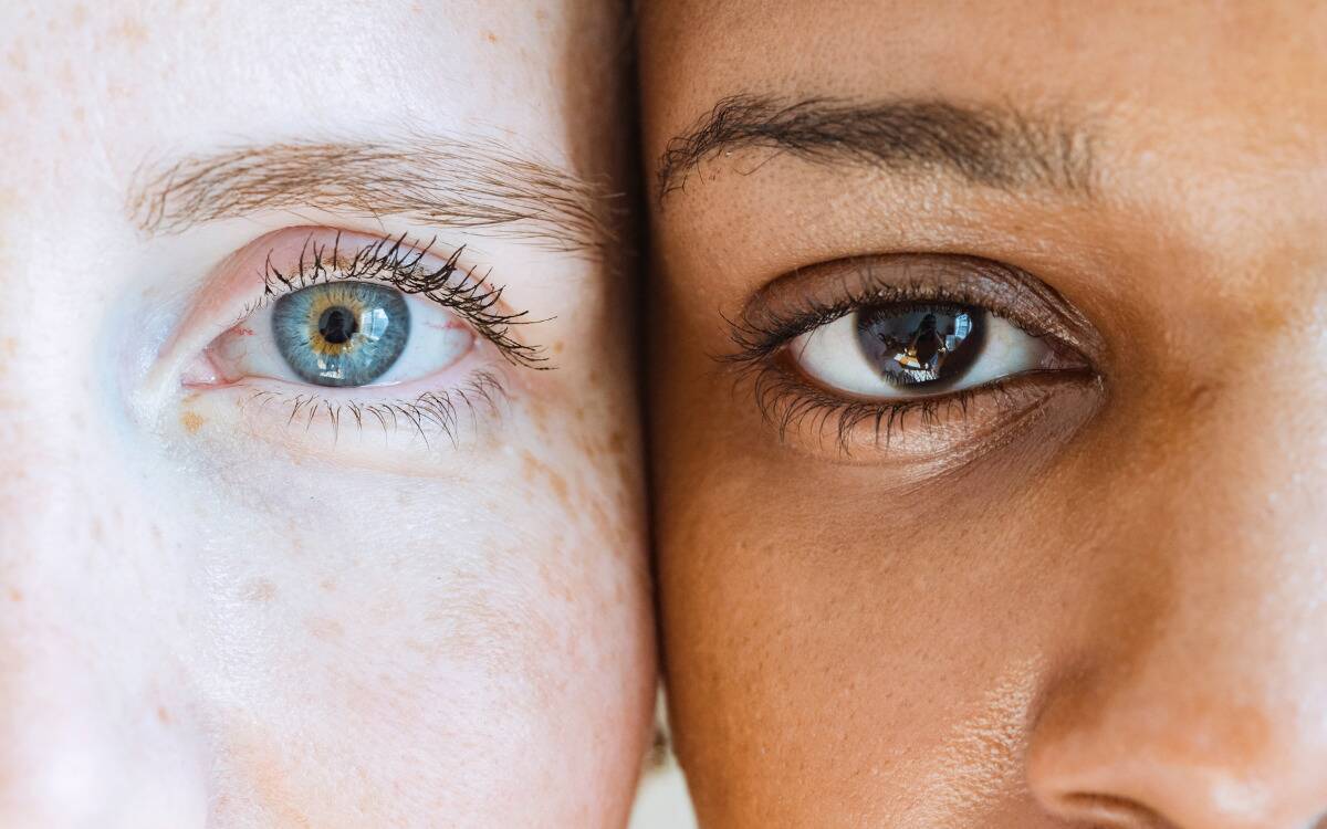 Two people with their faces pressed into one another, a closeup of their side by side eyes.