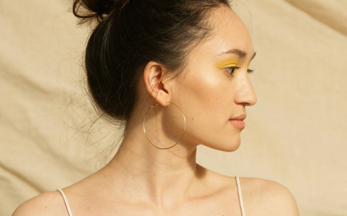 A woman in yellow eye makeup looking off to the right, showing her side profile.