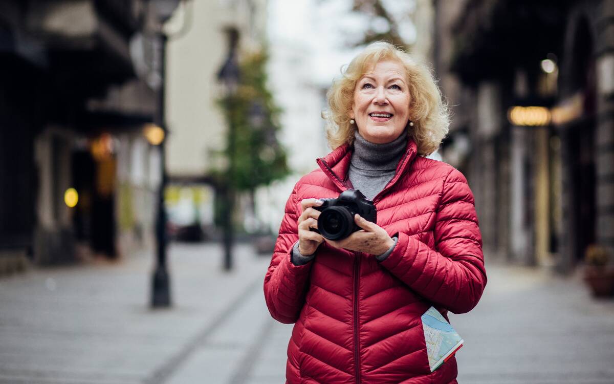 A woman walking through a city street holding a camera.