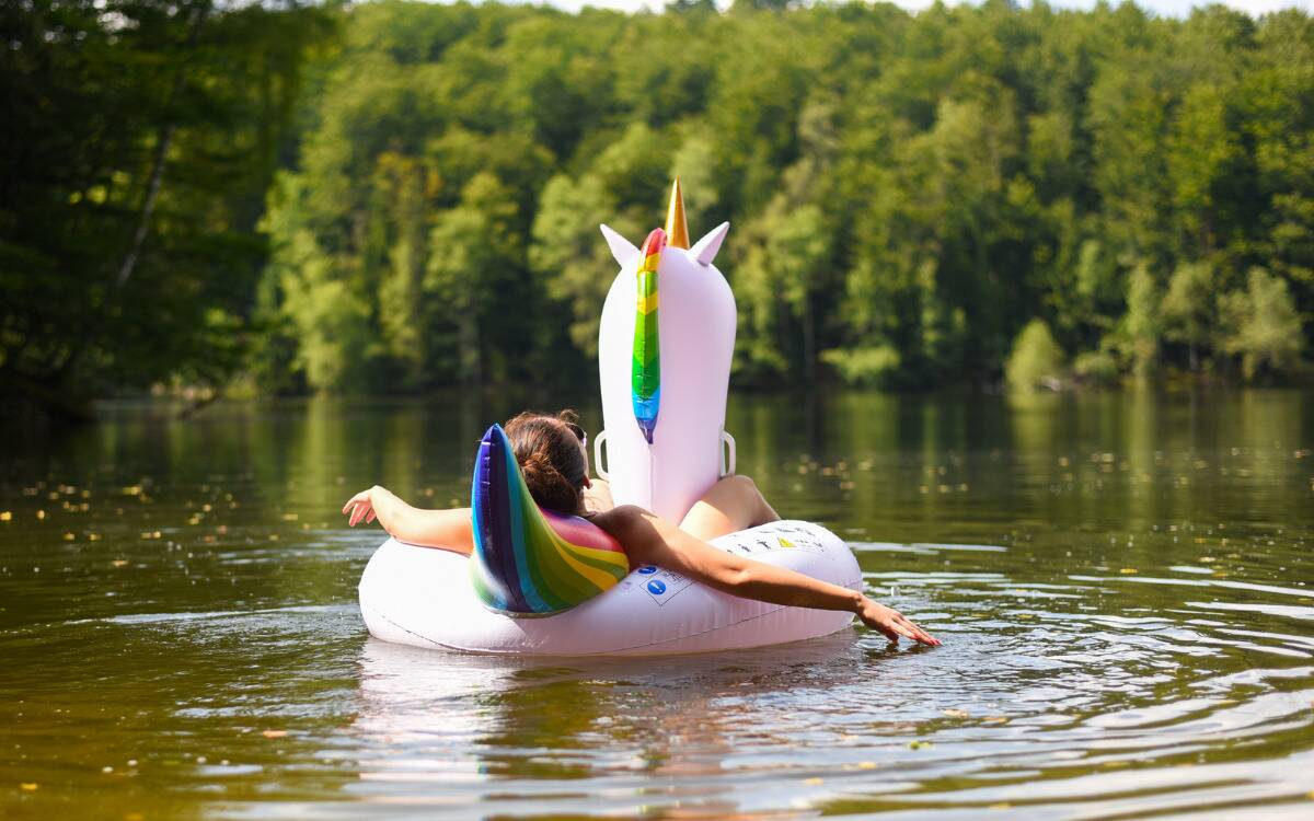 A woman relaxing in a large unicorn floatie, floating in a lake.