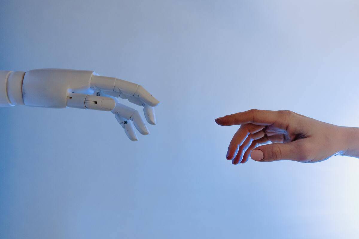 A robot and a human hand reaching out for one another.