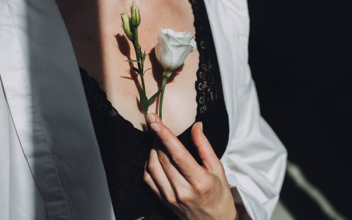 A woman holding a white rose to her chest.