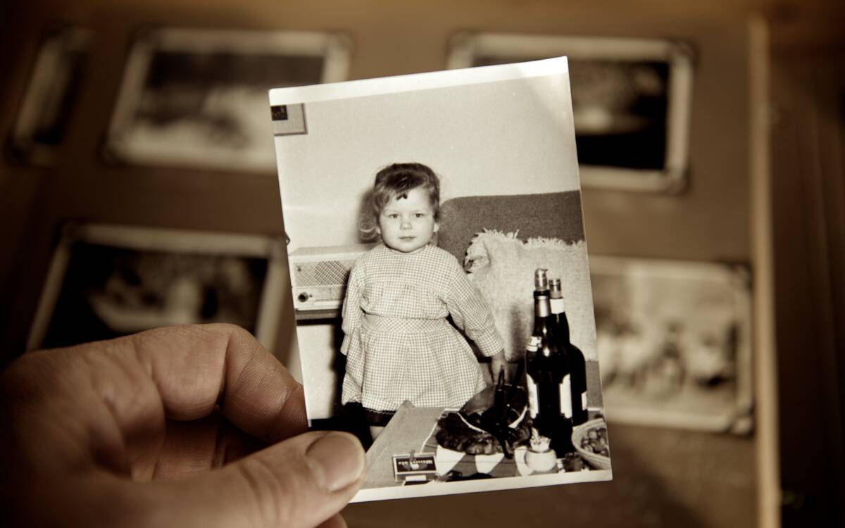 Someone holding up a black-and-white childhood photo of themselves.