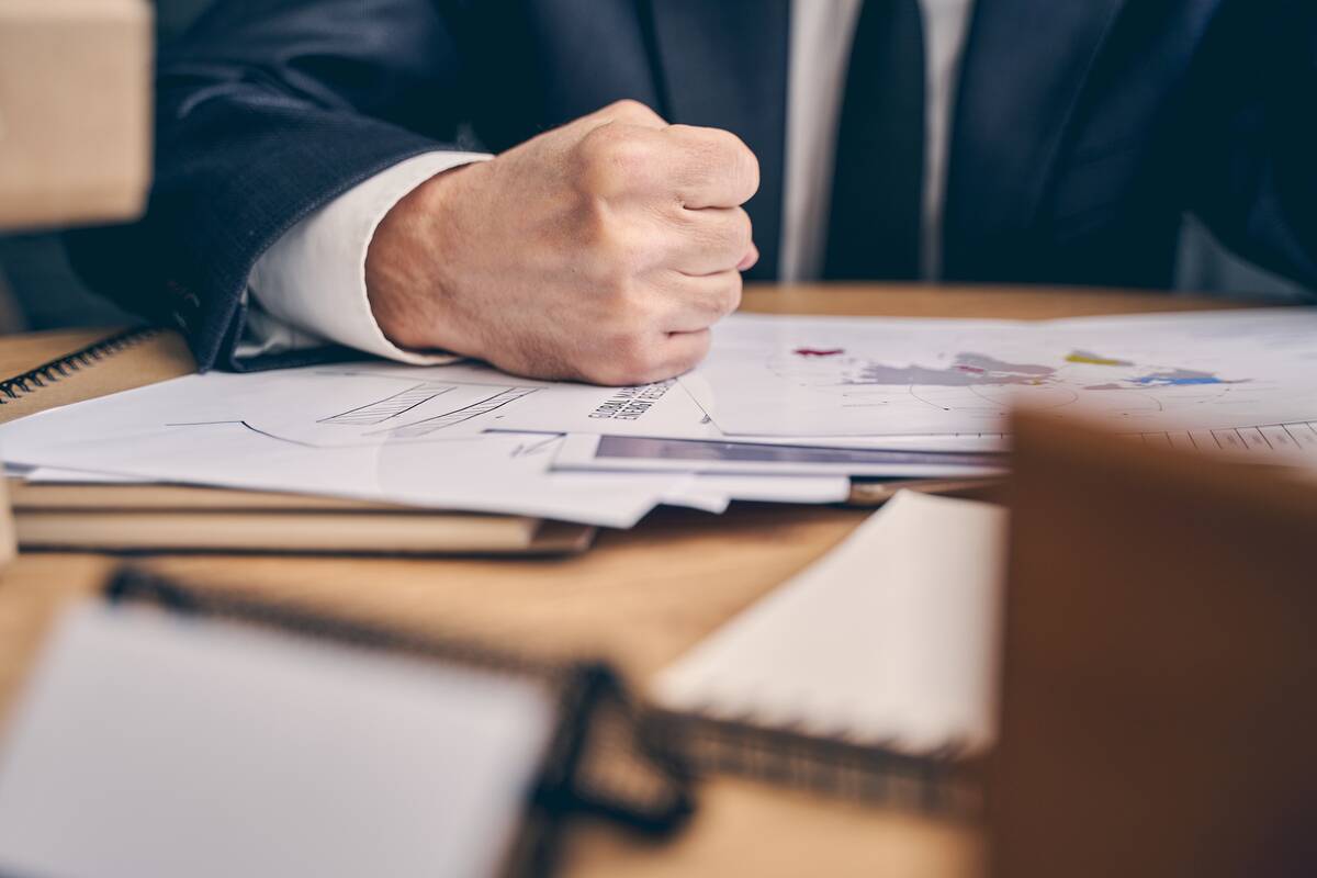 Close up of serious office worker making fist while working at his business plan,