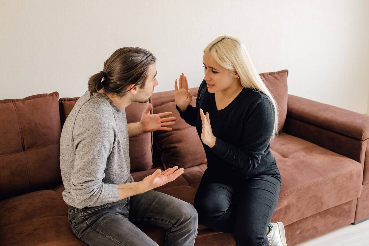 A couple arguing while sitting on a couch.