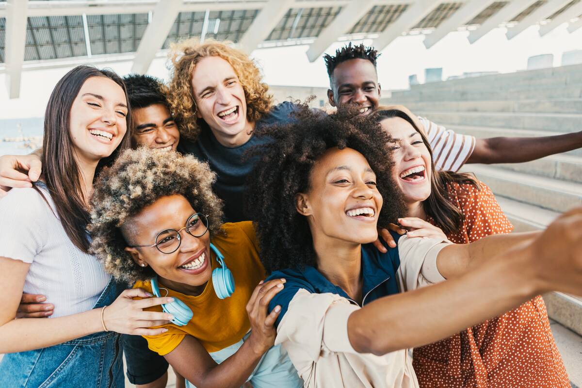 A group of friends all posing together to fit within a selfie.