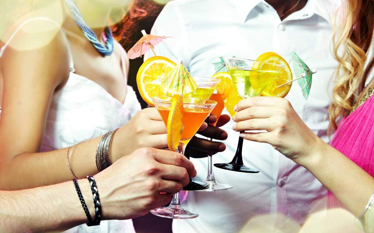 Friends cheersing colorful cocktails at an event.