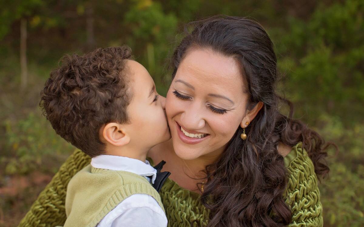 A young boy kissing his mother on the cheek.