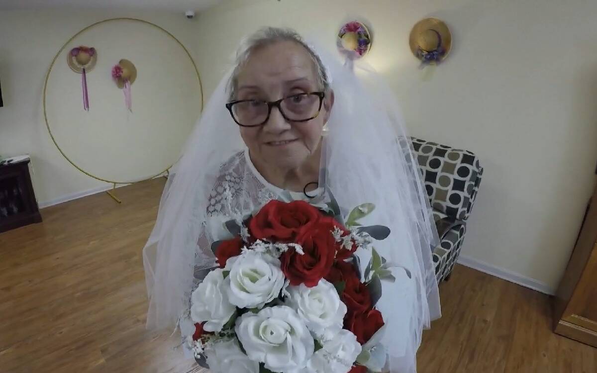Fideli in her wedding dress on the day of the ceremony, holding her bouquet.