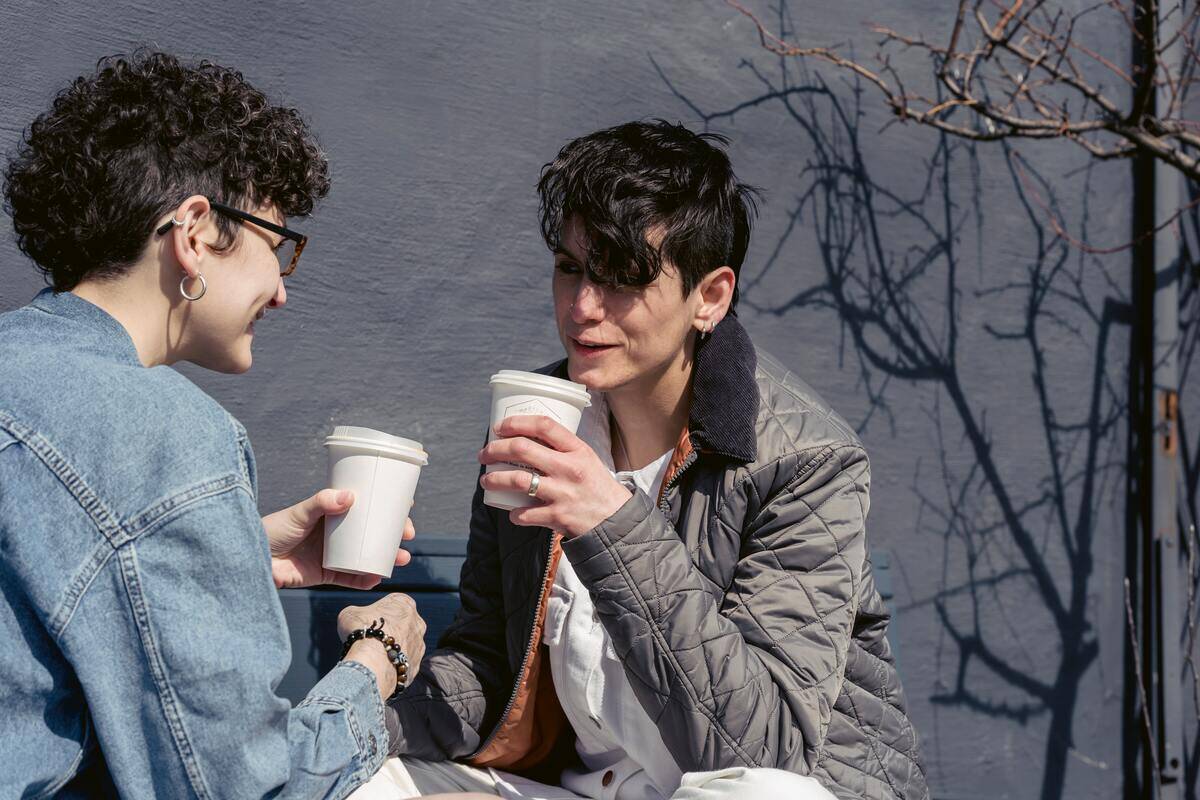 Two people talking over cups of coffee.
