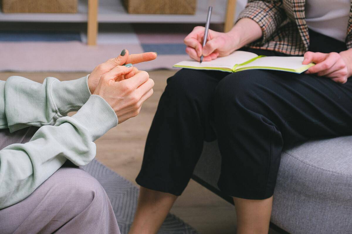 Someone speaking to a therapist as the therapist jots notes down.