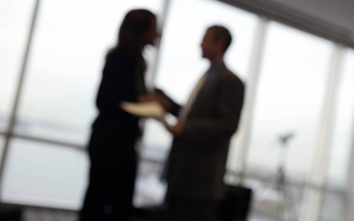 A blurred image of a man and woman in an office.