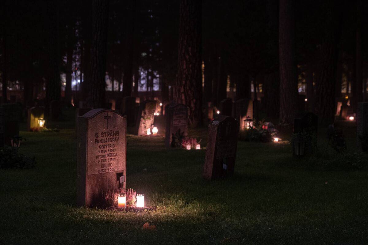A cemetery at night, most of the headstones lit up with candles.
